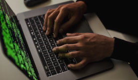 two hands typing on a laptop computer.